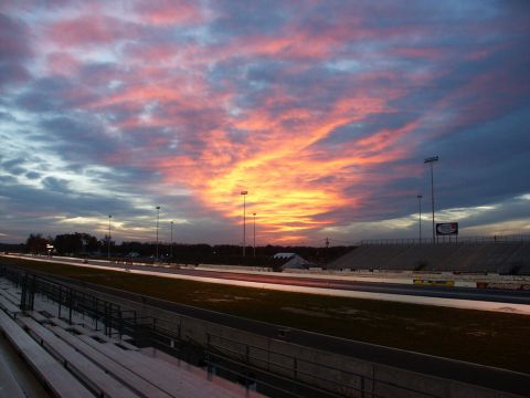 2001 Mercury Grand Marquis - A drag strip is viewed at sunset with a vibrant sky and stadium seating.