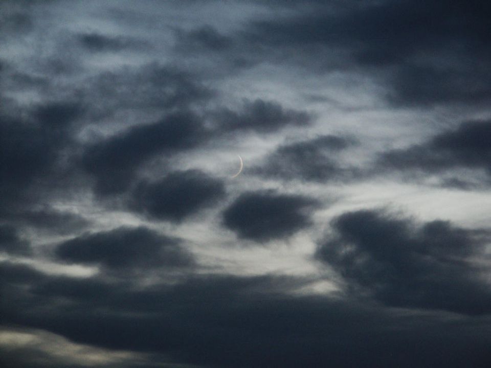 Cloudy sky with a crescent moon visible