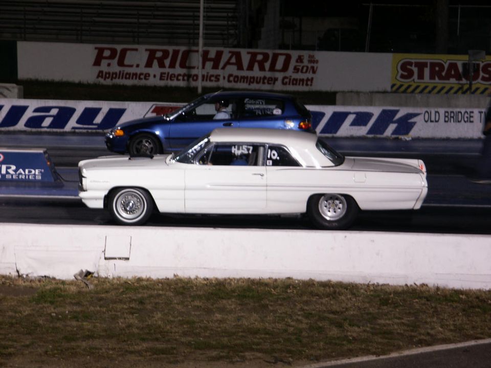 White classic coupe with racing numbers on door, side view on drag strip