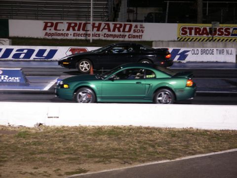 2001 Mercury Grand Marquis - Two cars compete on a drag strip, with a green Ford Mustang in the foreground.