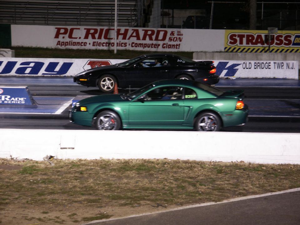Green 2001 Ford Mustang GT racing a black car on a drag strip