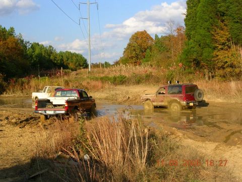 1989 Ford Bronco II - A red 1989 Ford Bronco II navigates a muddy off-road course alongside other vehicles.