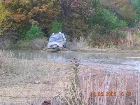 1989 Ford Bronco II - This 1989 Ford Bronco II is stuck in a muddy puddle, surrounded by dry grass and trees.