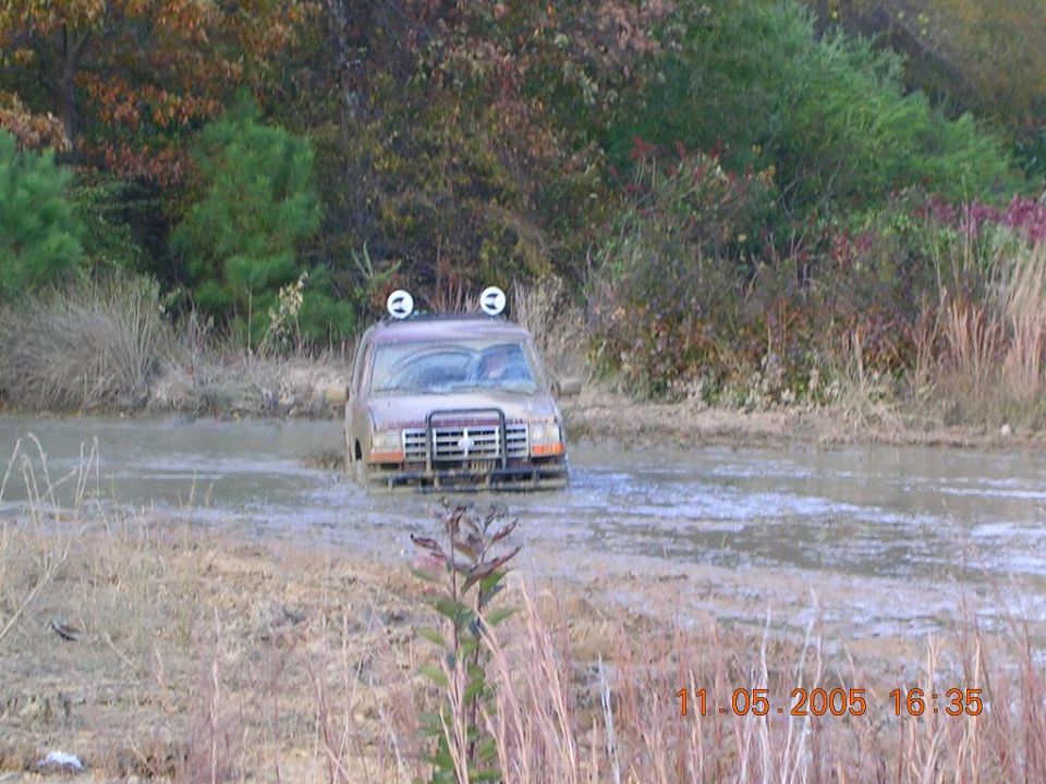 Brown 1989 Ford Bronco II stuck in mud, front view with brush guard and roof lights