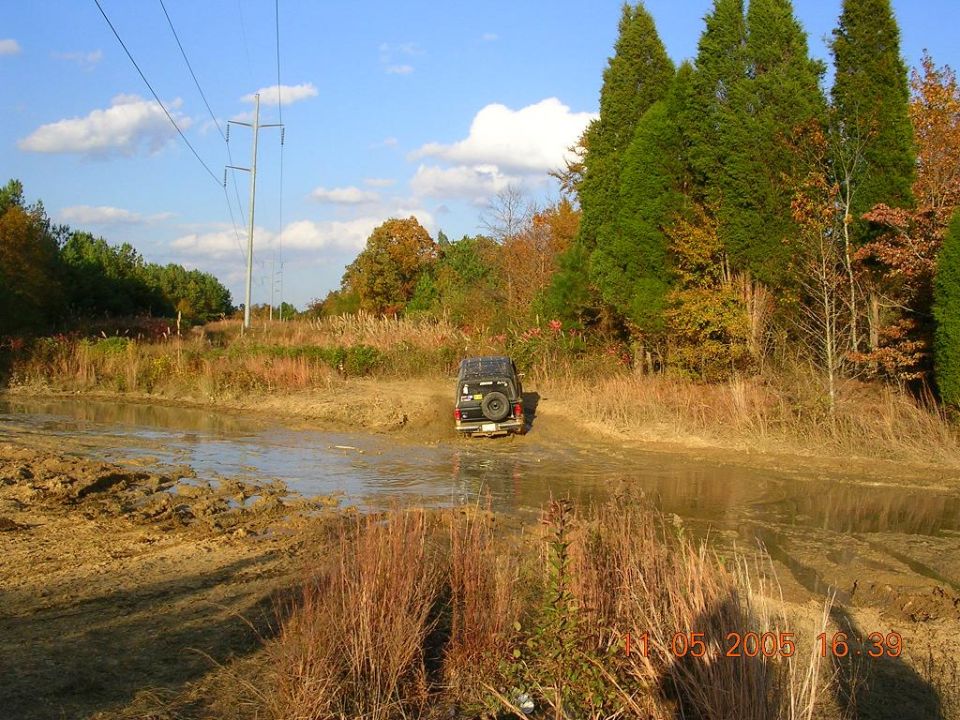 Black 1989 Ford Bronco II driving through mud puddle