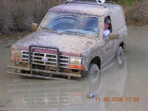 1989 Ford Bronco II - A 1989 Ford Bronco II is stuck in a muddy puddle, with a person in the driver's seat.