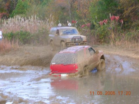 1989 Ford Bronco II - Two SUVs navigate a challenging mud pit during an off-road excursion.