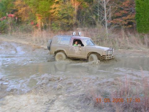 1989 Ford Bronco II - Muddy 1989 Ford Bronco II navigates a water obstacle on an off-road trail.