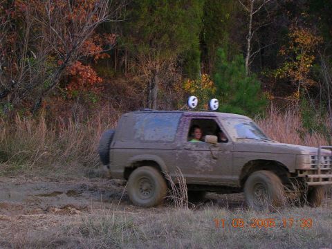 1989 Ford Bronco II - A 1989 Ford Bronco II navigates a muddy trail with its occupants visible through the windows.