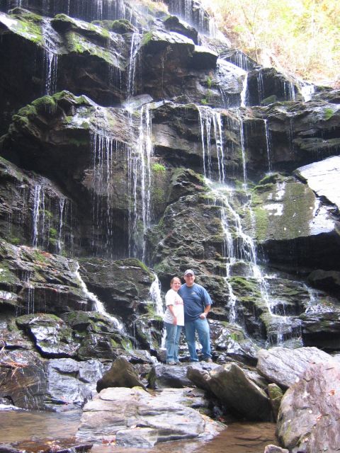 1985 Ford LTD Crown Victoria - A scenic view of a waterfall with two people posing for a photo at its base.