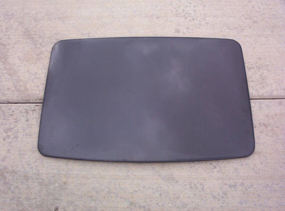 Dark gray car roof panel with rounded corners, lying flat on a concrete surface