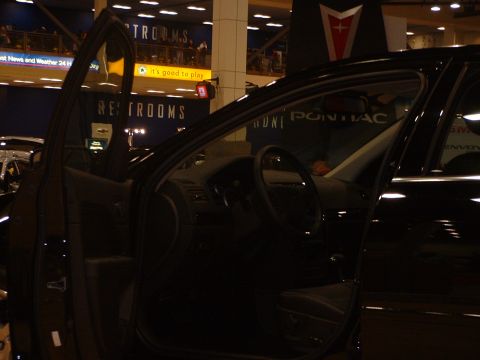 1999 Ford Crown Victoria - The interior of a black car is shown with the driver's side door open, revealing the dashboard and steering wheel.