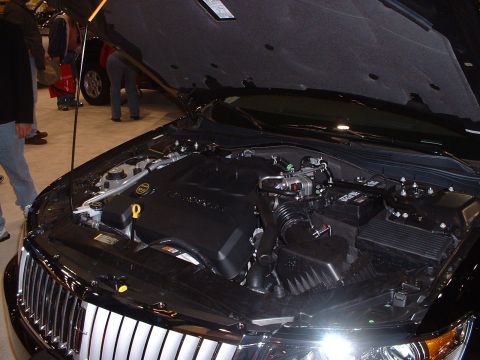 1999 Ford Crown Victoria - The engine bay of a black car is displayed, with a prominent chrome grille in the foreground.