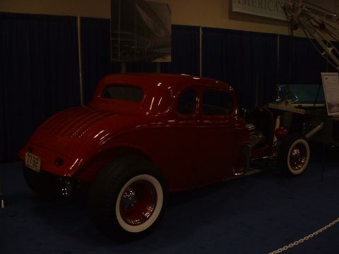 1999 Ford Crown Victoria - A red coupe hot rod is displayed indoors, whitewall tires and a custom license plate.