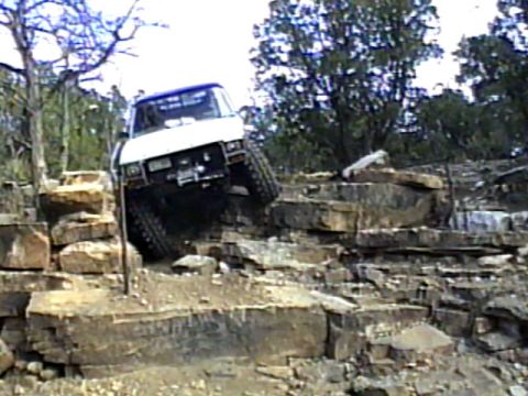 1981 Ford Bronco - A white SUV navigates a difficult rocky terrain.