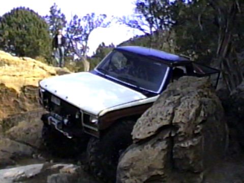 1981 Ford Bronco - This off-road vehicle is navigating a challenging rocky path with a person observing from a higher vantage point.
