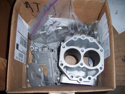 1983 Ford Bronco - Unidentified engine parts, possibly for a carburetor, are packed in a cardboard box.