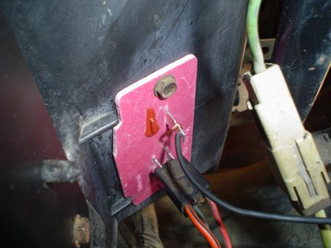 1984 Ford Bronco - Close-up of a wiring harness connected to a pink plate, showing exposed wires and connectors.