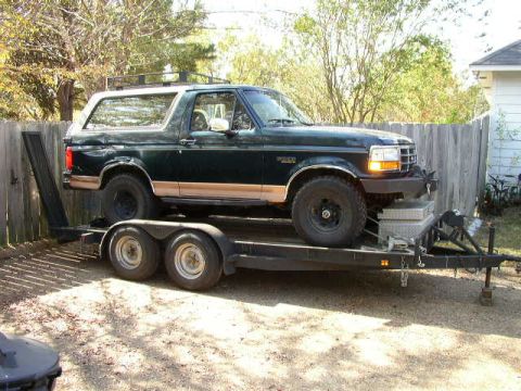 1995 Ford Bronco - A dark green Ford Bronco is loaded onto a trailer, ready for transport.