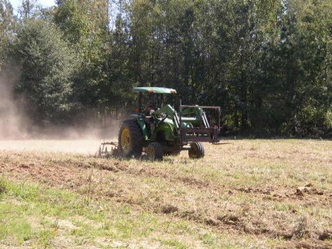 1995 Ford Bronco - A tractor is seen plowing a field, with trees in the background.