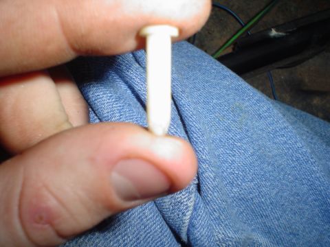 1984 Ford Bronco - A white plastic fastener is held in a person's fingers, with blue denim and wiring visible in the background.
