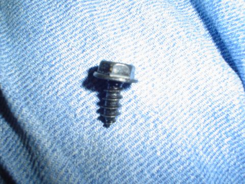 1984 Ford Bronco - A single screw is shown against a textured blue fabric background.