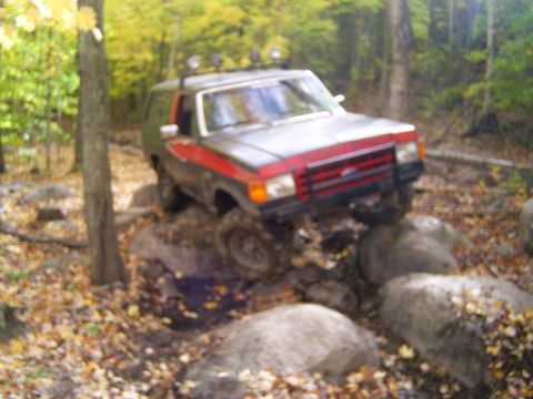 1977 Ford F-150 - This SUV is navigating a rocky trail in a wooded area during autumn.