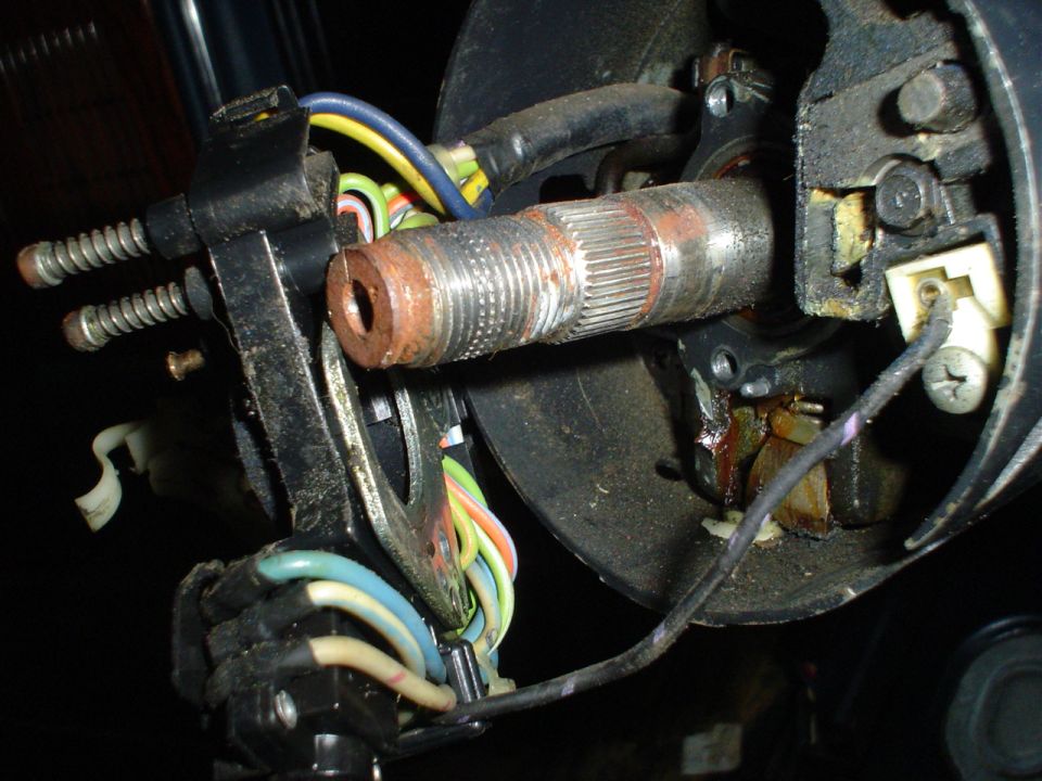 Close-up of a rusty steering column shaft and electrical connectors with colorful wires