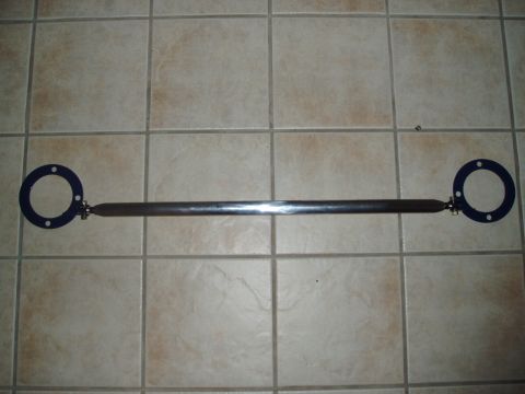 1993 Ford Taurus - Aftermarket strut tower brace with blue mounting plates shown on tiled floor.