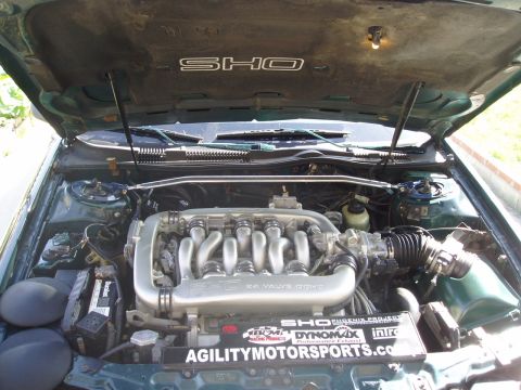 1993 Ford Taurus - The engine bay of a green vehicle displays SHO badging and a V6 engine with aftermarket parts.