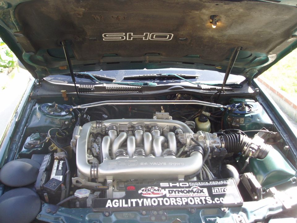 Green engine bay with SHO badging on the hood and a V6 engine. Agilitymotorsports.com sticker visible