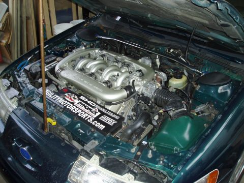 1993 Ford Taurus - Engine bay of a 1993 Ford Taurus, its V6 engine and a strut tower brace.