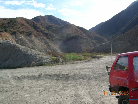 1985 Ford Bronco - A red SUV is parked on a dirt road with mountains in the background. A date stamp reads 11.08.2005.