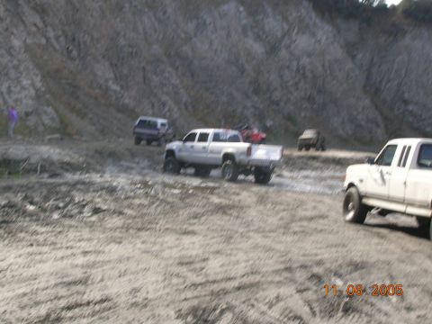 1985 Ford Bronco - Multiple trucks navigate a muddy terrain near a rocky hillside, with a visible date stamp of November 6, 2005.