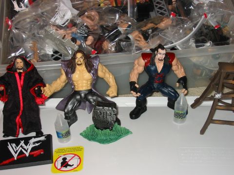 1991 Ford Bronco - Collection of wrestling action figures displayed with accessories, including a tombstone and WWE logo.