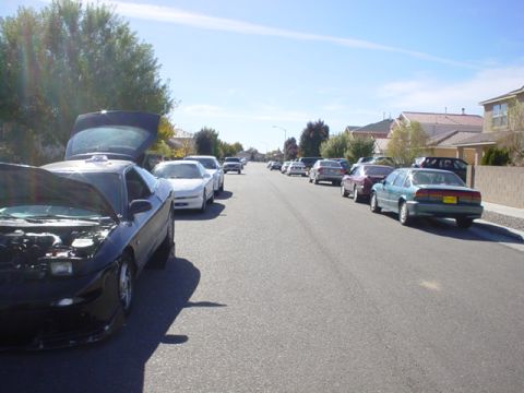 1993 Ford Probe - A black 1993 Ford Probe is parked on the street with its hood and trunk open, alongside other vehicles.