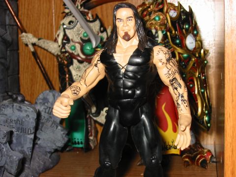 1991 Ford Bronco - A wrestling action figure stands in front of a display of other figures and tombstone props.