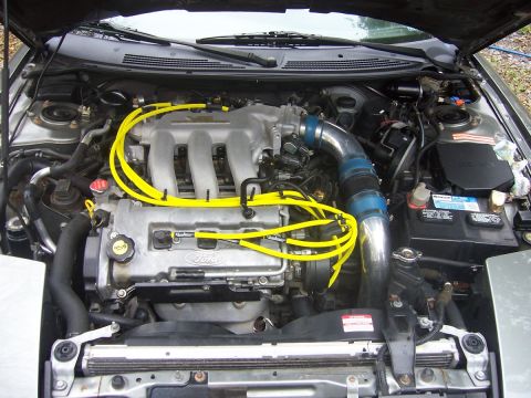 1996 Ford Probe - The engine bay features a Ford V6 engine with bright yellow spark plug wires and an aftermarket cold air intake system.