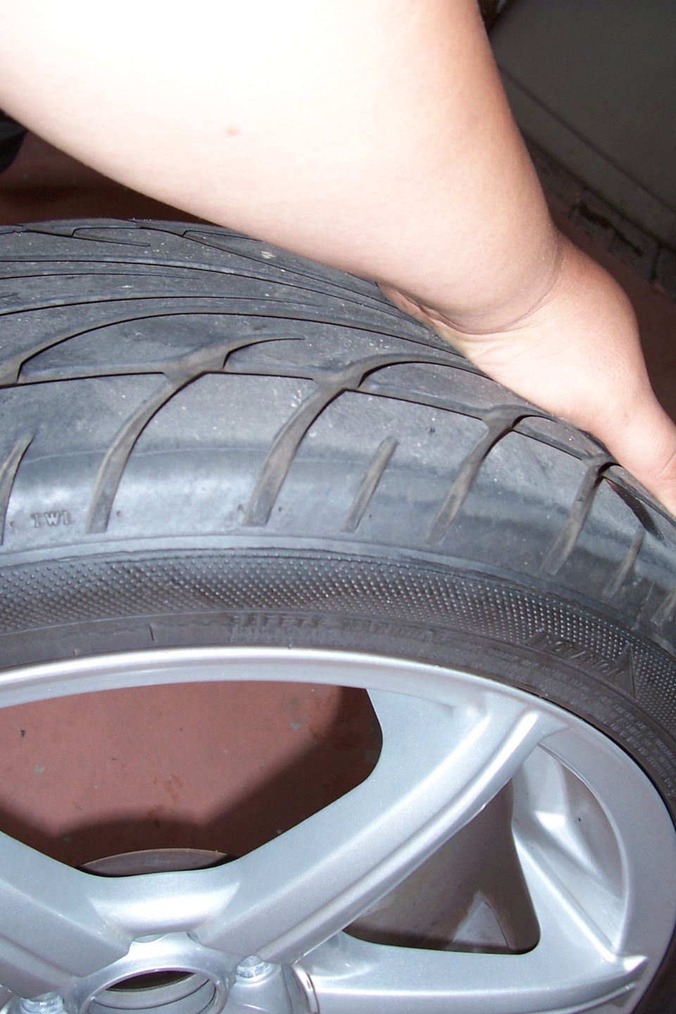 Close-up of a worn tire on a silver alloy wheel