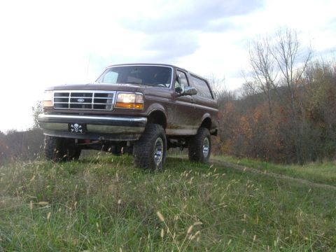 1993 Ford Bronco - A brown 1993 Ford Bronco is shown in a three-quarter front view, lifted and ready for off-road terrain.