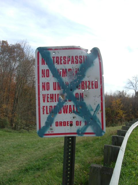 1993 Ford Bronco - A weathered sign with bullet holes and spray paint warns against trespassing and unauthorized vehicles.