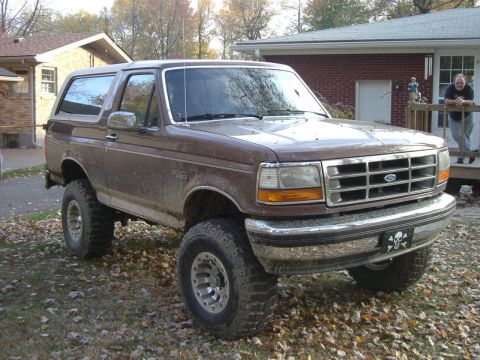 1993 Ford Bronco - A lifted Ford Bronco sits in a yard with fallen leaves scattered around.