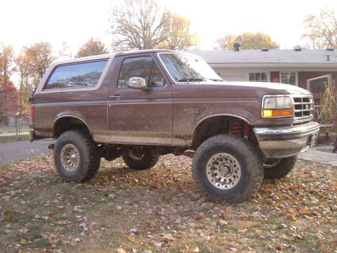 1993 Ford Bronco - This lifted Ford Bronco has a brown exterior and is shown from a three-quarter front view.
