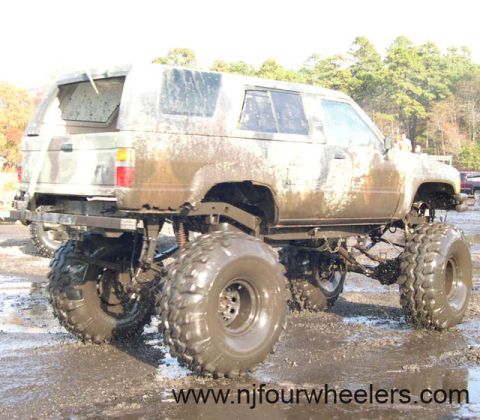 1987 Suzuki Samurai - This heavily modified SUV is covered in mud, showing off its lifted suspension and oversized tires.