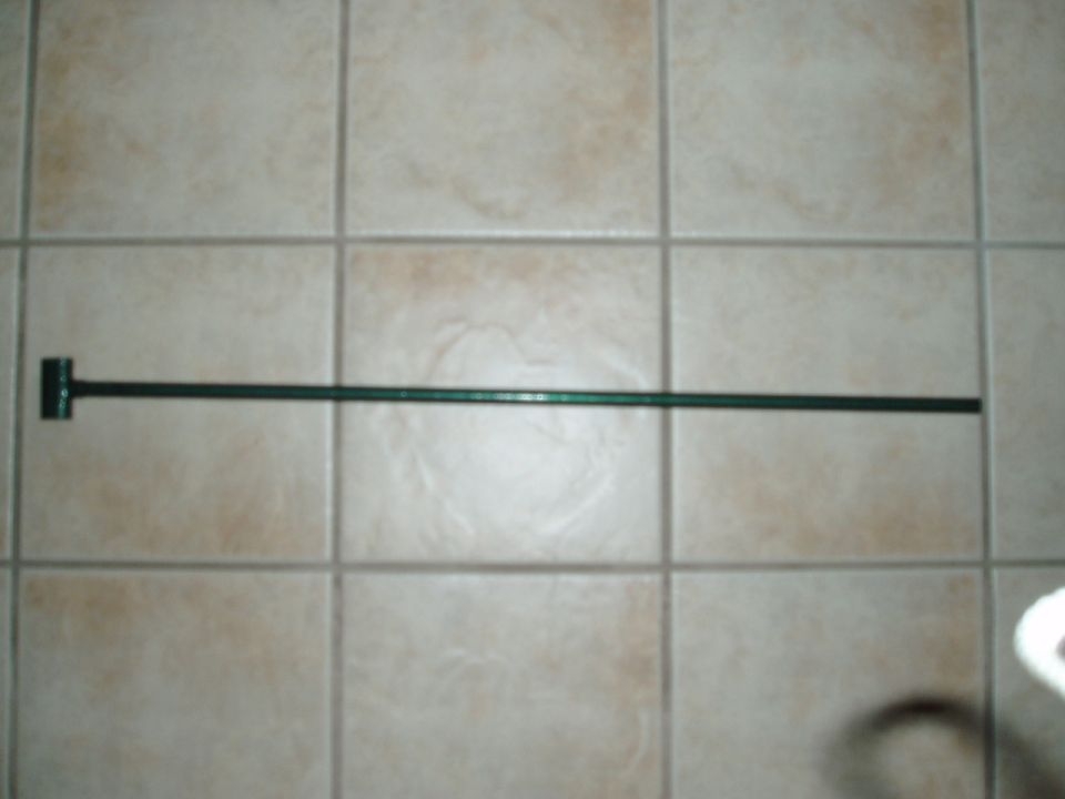 Dark green metal bar with T-bracket on tiled background