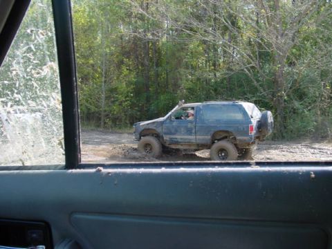 1992 Chevrolet S10 - SUV navigates a muddy trail with trees in the background.
