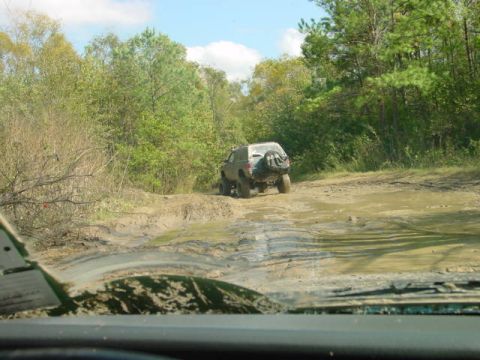 1992 Chevrolet S10 - Off-roading in a 1992 Chevrolet S10 on a wet, muddy trail surrounded by trees.