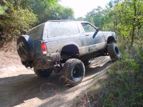 1992 Chevrolet S10 - This SUV is shown off-roading on a dirt path surrounded by trees.