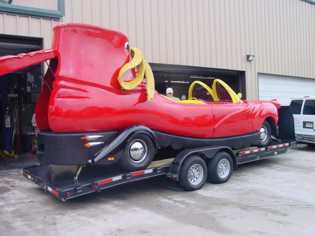 Red novelty car shaped like a boot on a trailer, yellow interior accents