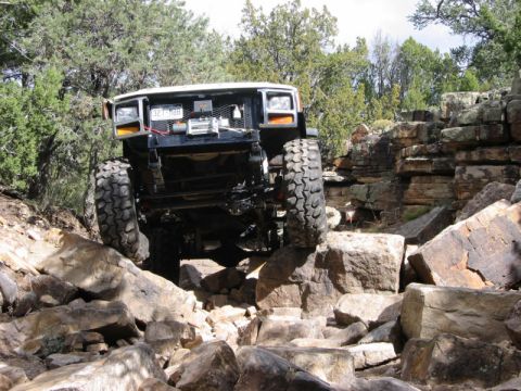1981 Ford Bronco - This modified vehicle is shown off-roading over large rocks.